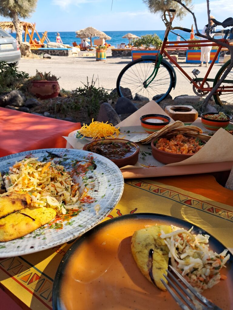 Vegan taco platter overlooking Perissa Beach in Santorini, bike, beach and sea in background