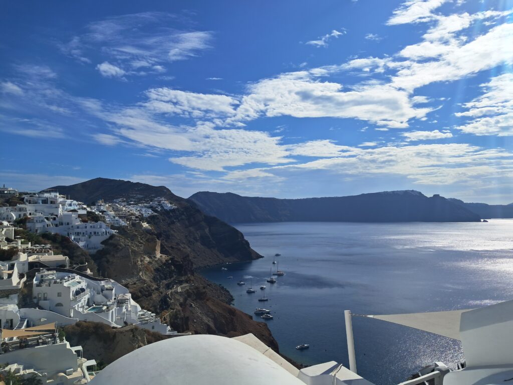 View over the Santorini caldera from Oia, with white cliffside buildings and boats anchored in the bay below