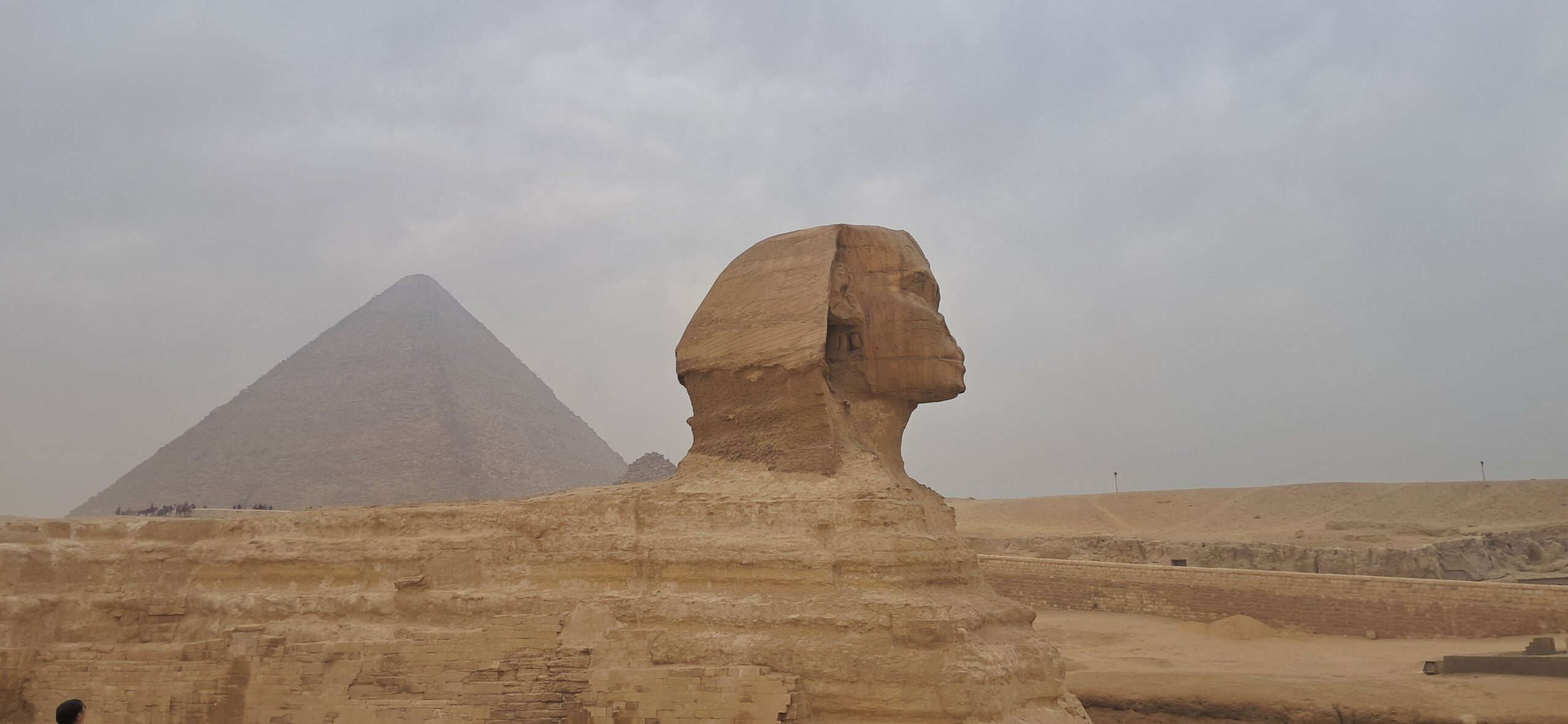 The Great Sphinx of Giza with a pyramid behind it, the area where camel and horse handlers gather for tourists