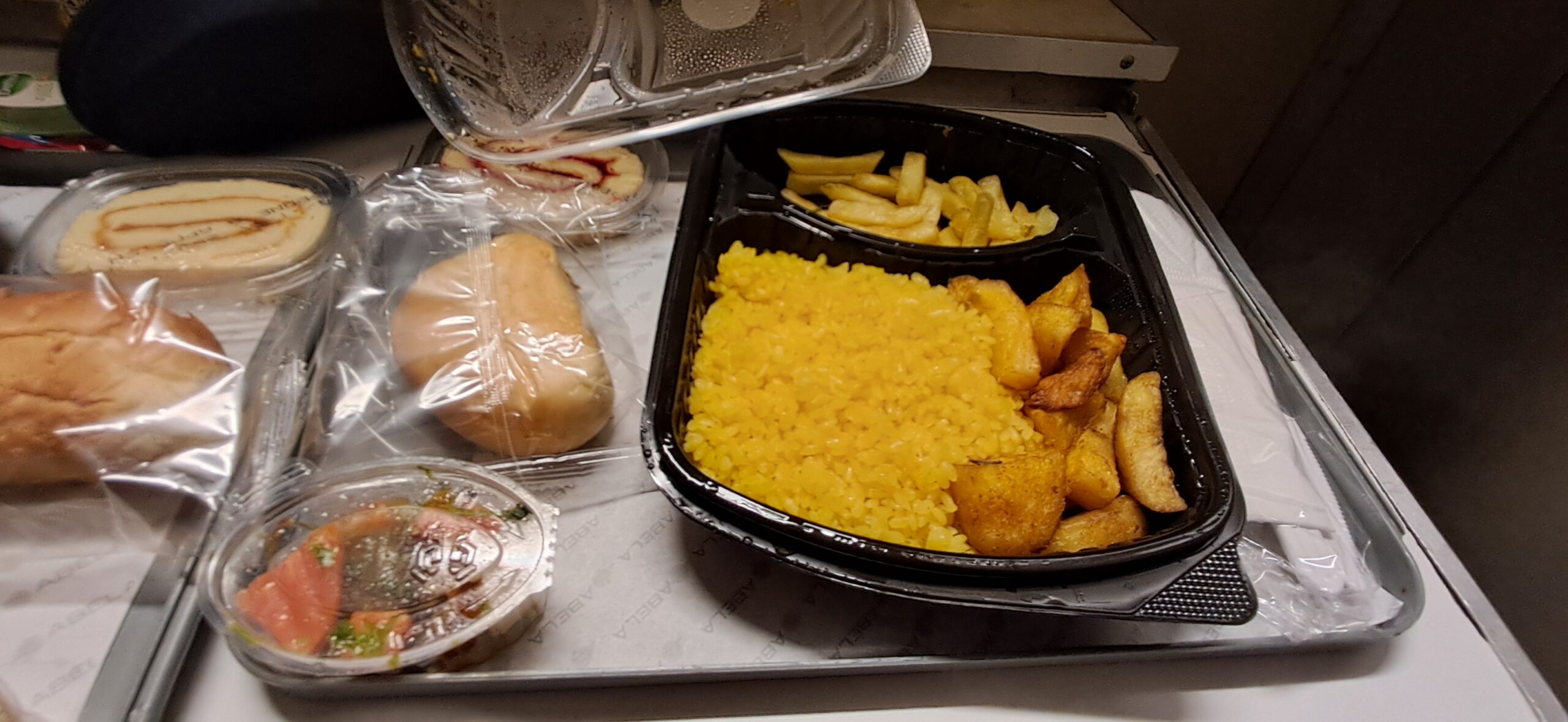 The vegan dinner tray on the Egypt sleeper train: rice, roasted potatoes, chips, pickled vegetables and bread rolls