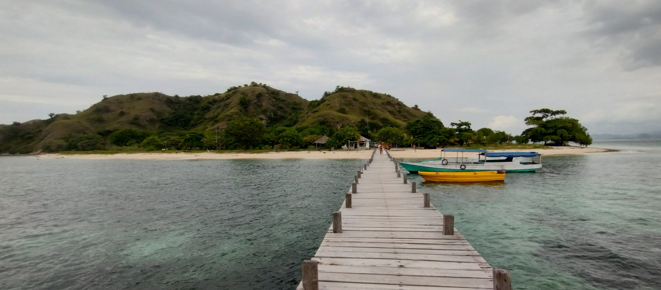 The long wooden jetty at Kanawa Island with boats moored alongside