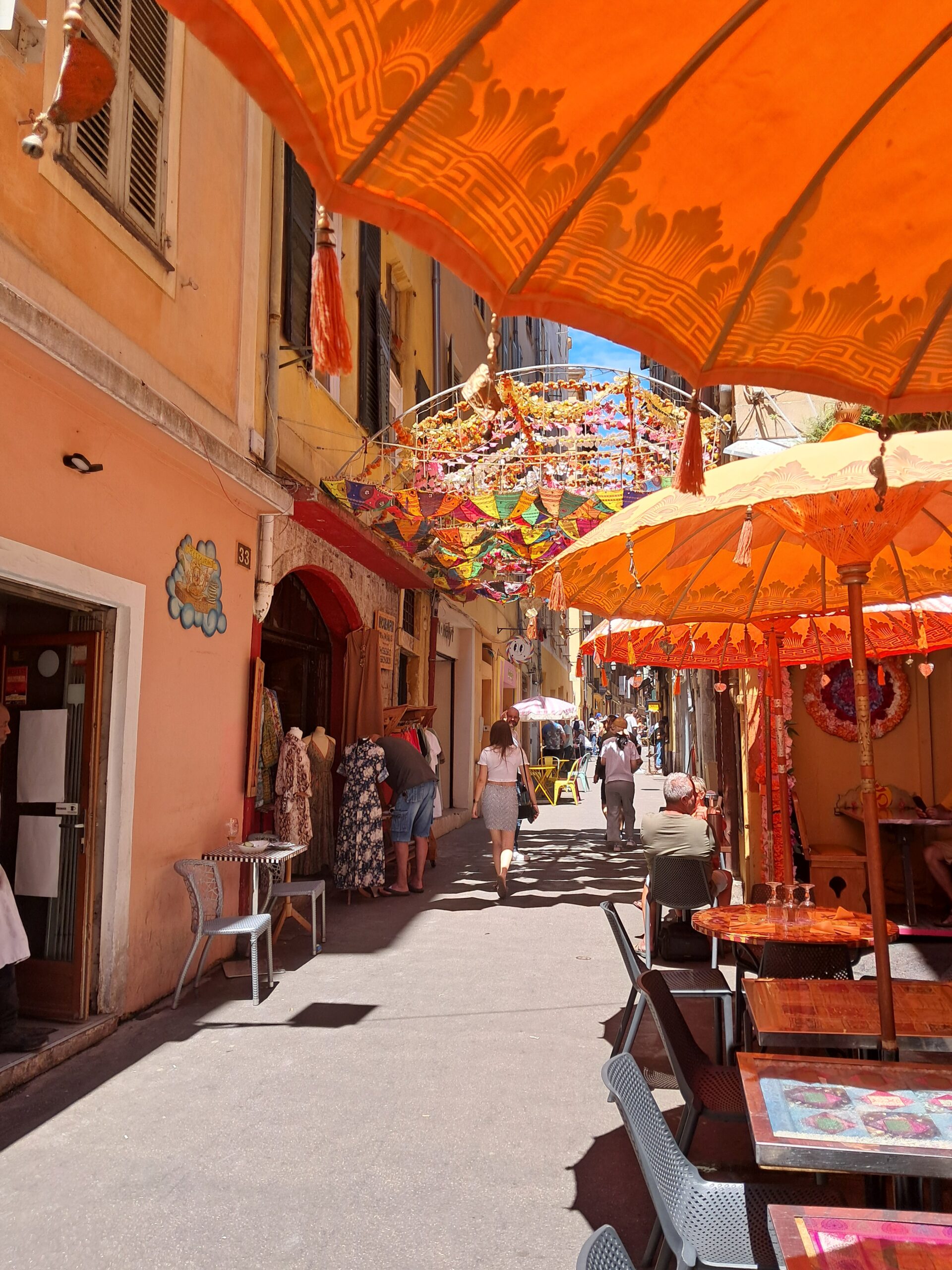 A narrow old town street in Vieux Nice with orange parasols