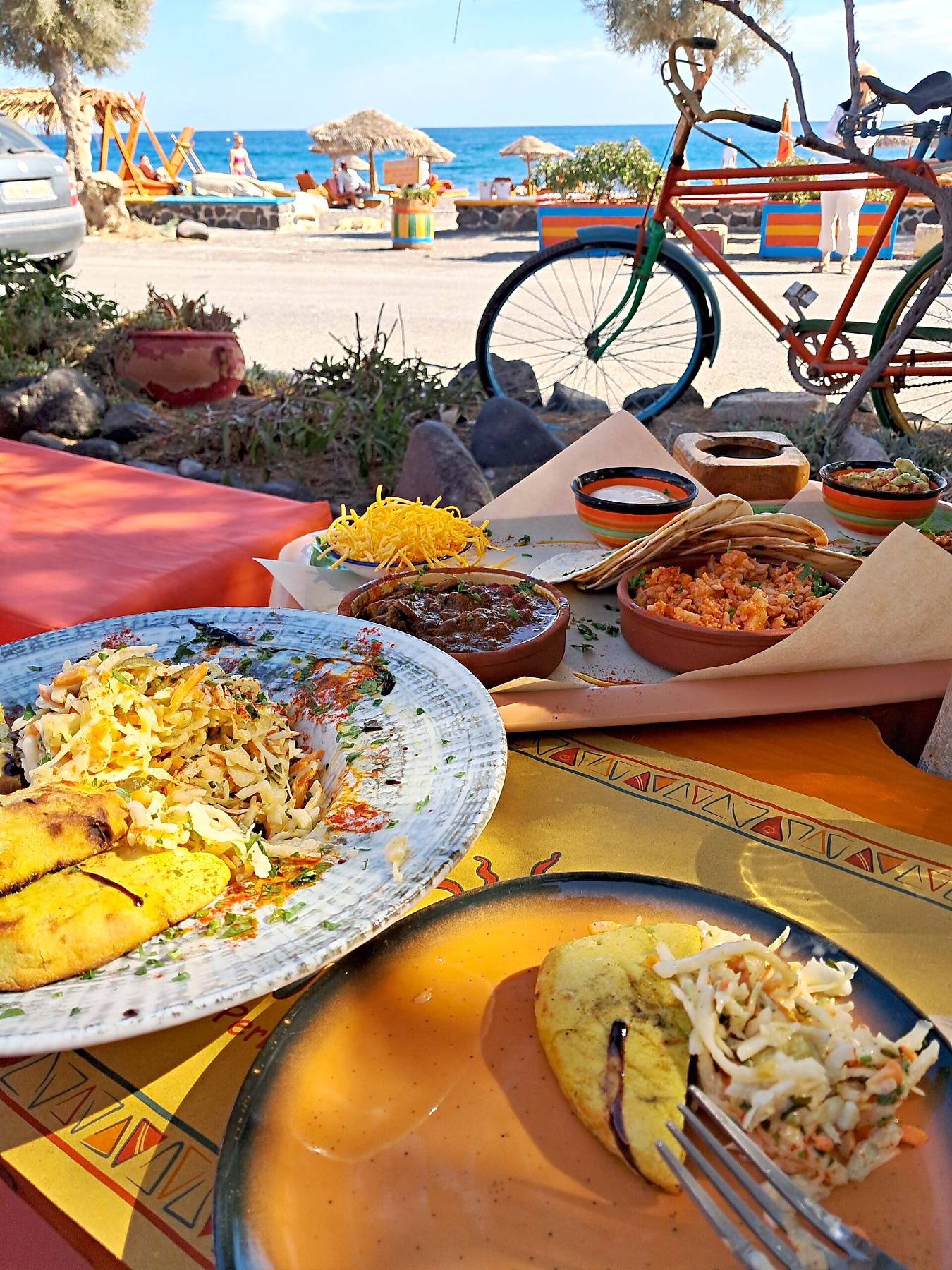 Colourful vegan spread at Tranquilo beachside restaurant in Perissa Santorini with the black sand beach and sea behind