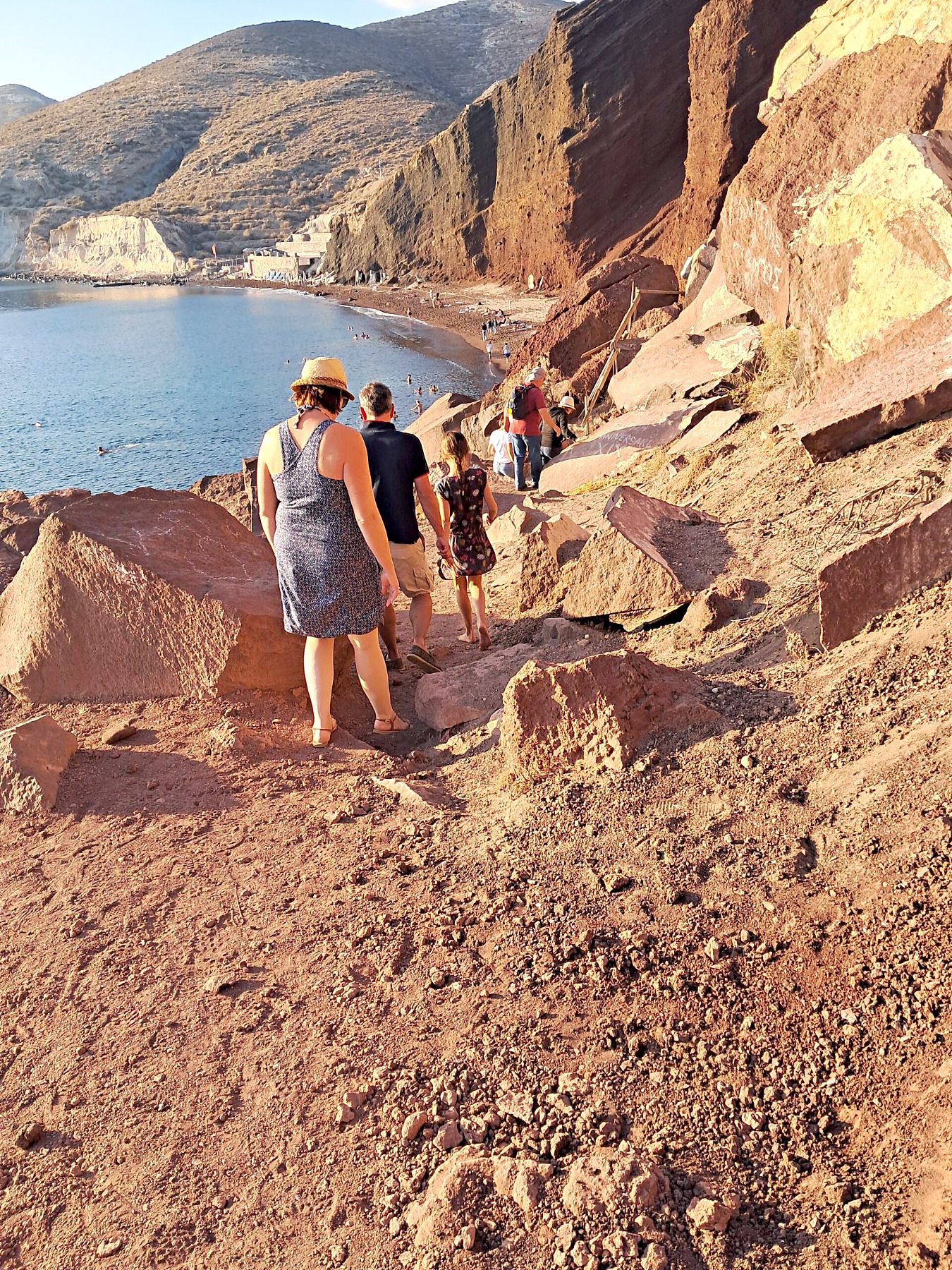 People walking the path down through the red volcanic cliffs to Red Beach, Santorini