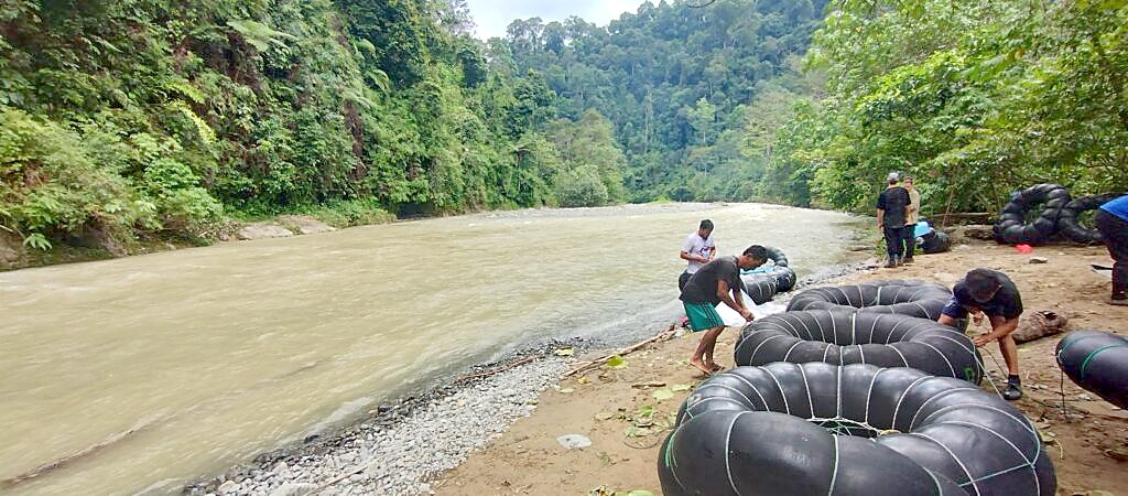 White water rafting back to Bukit Lawang on rubber tube rafts along the Bohorok River in the rain after two days of jungle trekking